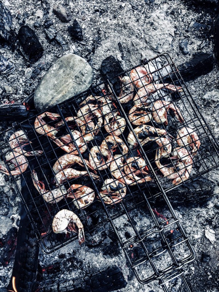 Spot prawns being grilled over fire coals